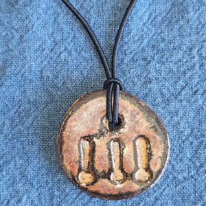 circular pendant with shiny copper glaze and three exclamation marks, imprinted and unglazed