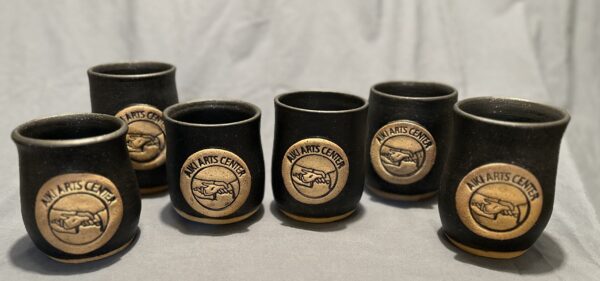 line of black cups with aiki arts center logo in center