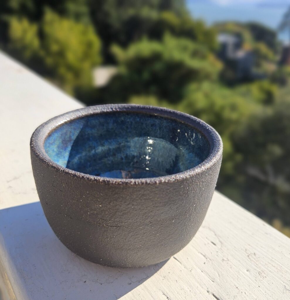 Small round bowl, exterior dark brown and unglazed, interior a vibrant blue
